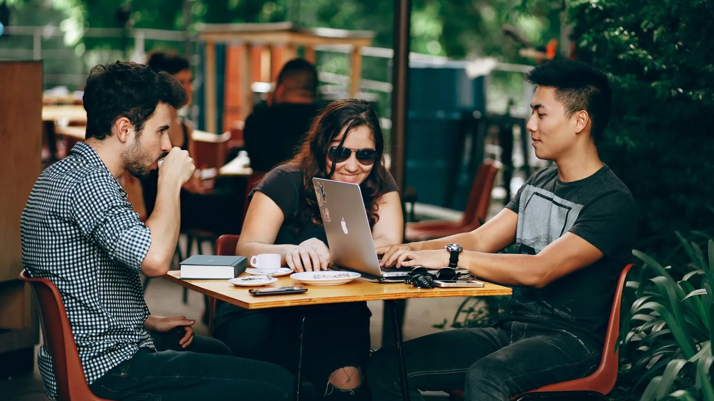 two men and a woman sitting and chatting at a table