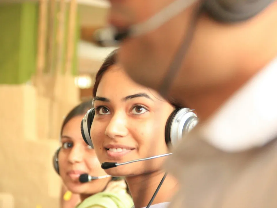 woman smiling wearing headset in between two people also wearing headsets