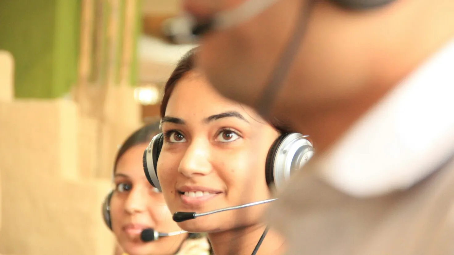 woman smiling wearing headset in between two people also wearing headsets