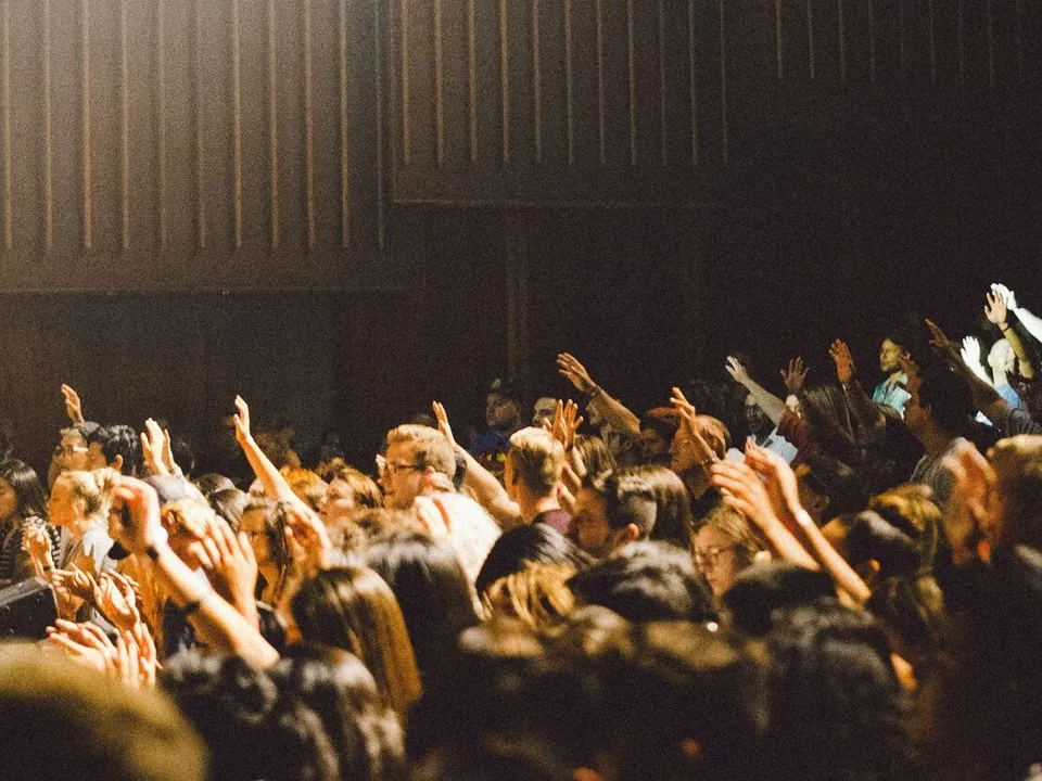 people raising their hands to ask questions in a lecture hall
