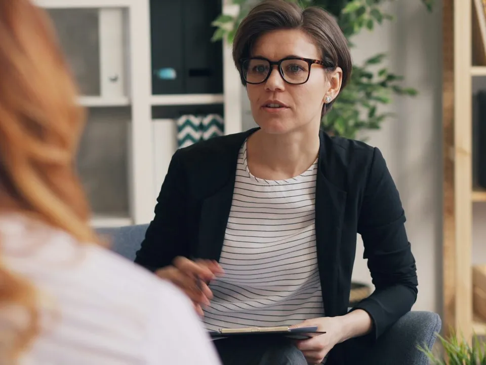 woman sitting on a couch and speaking to a woman facing her