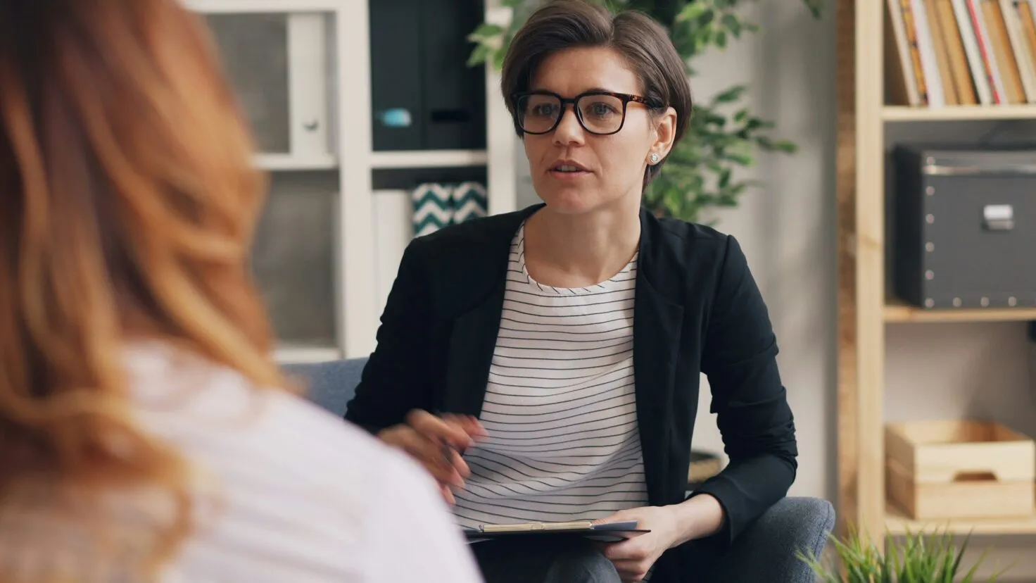 woman sitting on a couch and speaking to a woman facing her