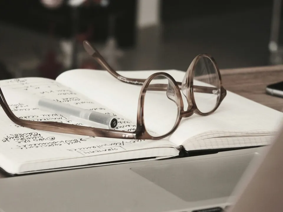 glasses with grey frames on top of an open book