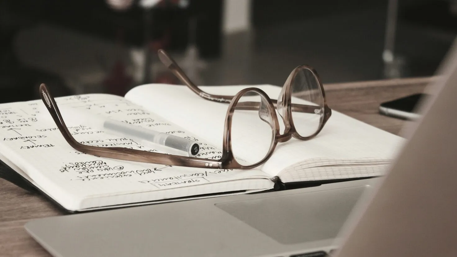 glasses with grey frames on top of an open book